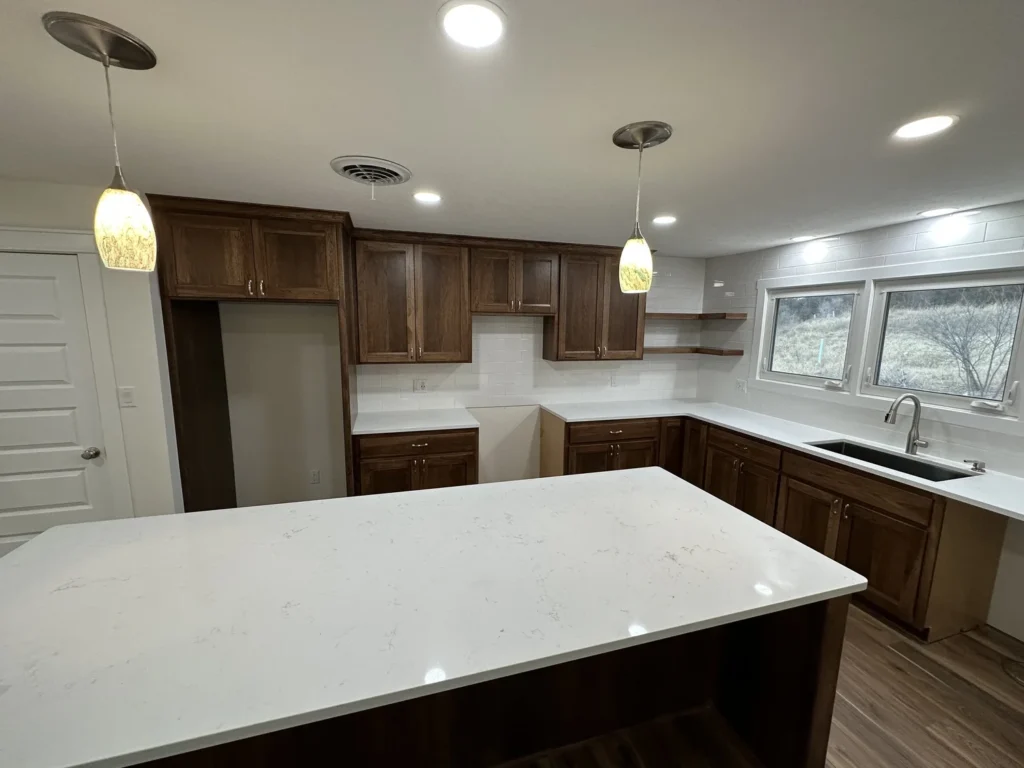 A newly remodeled kitchen with dark walnut cabinets and white countertops.